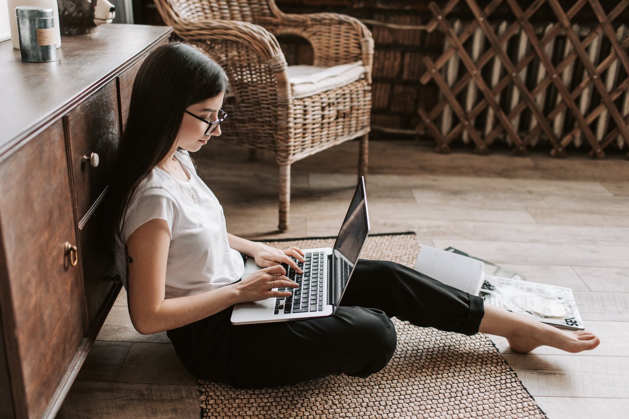 Positive young lady browsing laptop at home